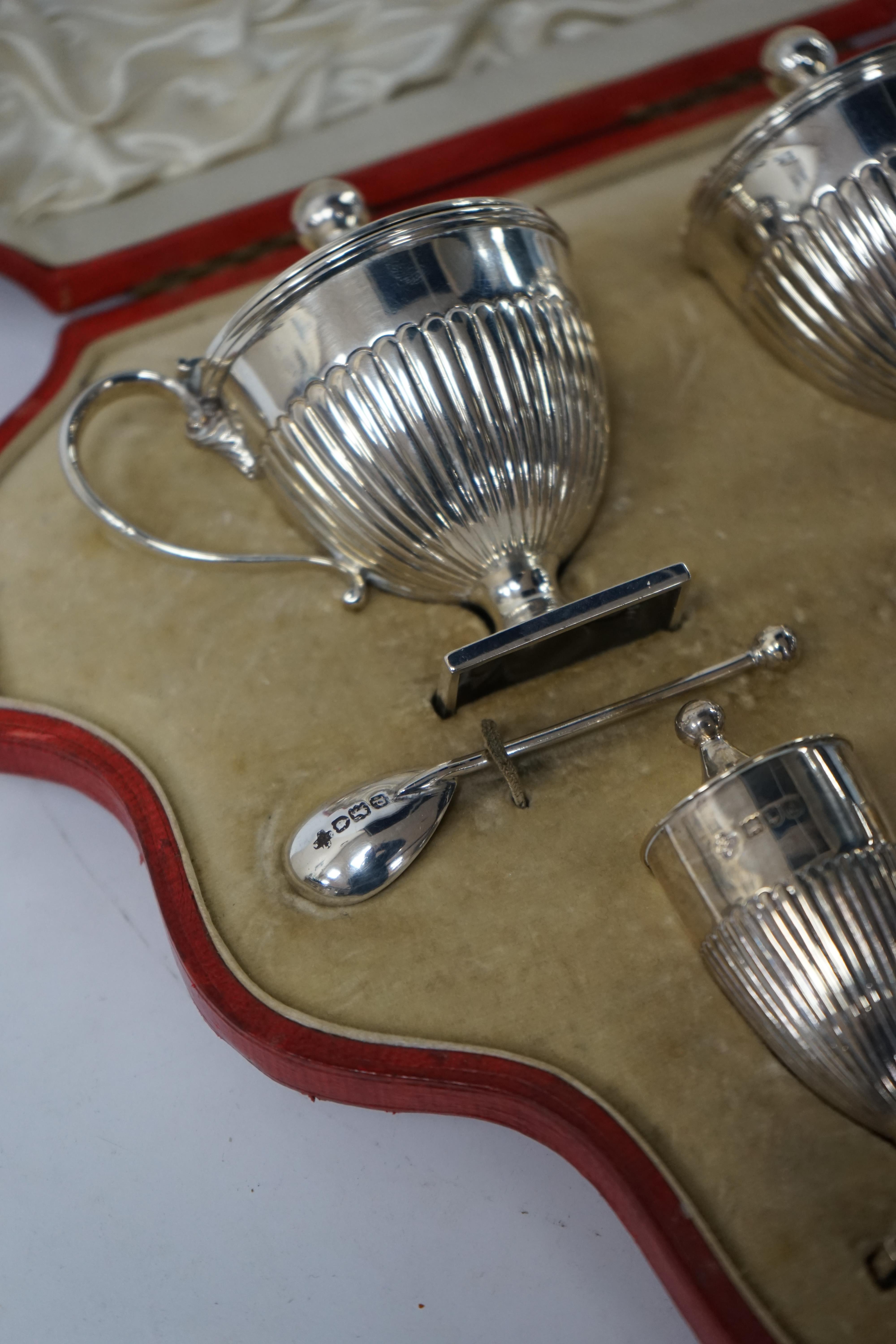 A cased late Victorian four piece silver cruet set with two spoons, by Mappin & Webb, London 1897/8, mustard pot, 83mm, glass liners differ and one is chipped. Condition - poor to fair to good